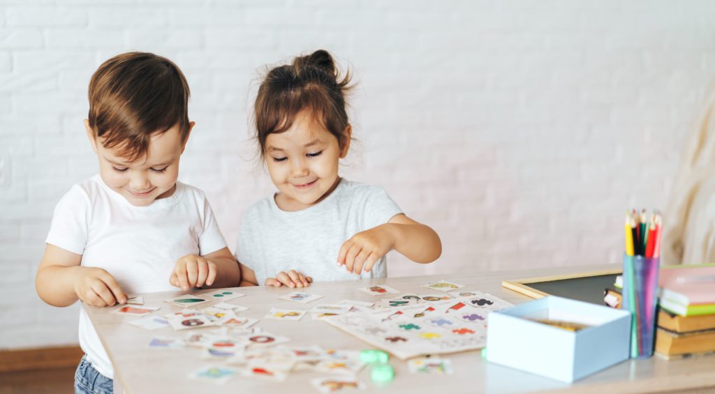 två barn står vid bord och leker med bild spel